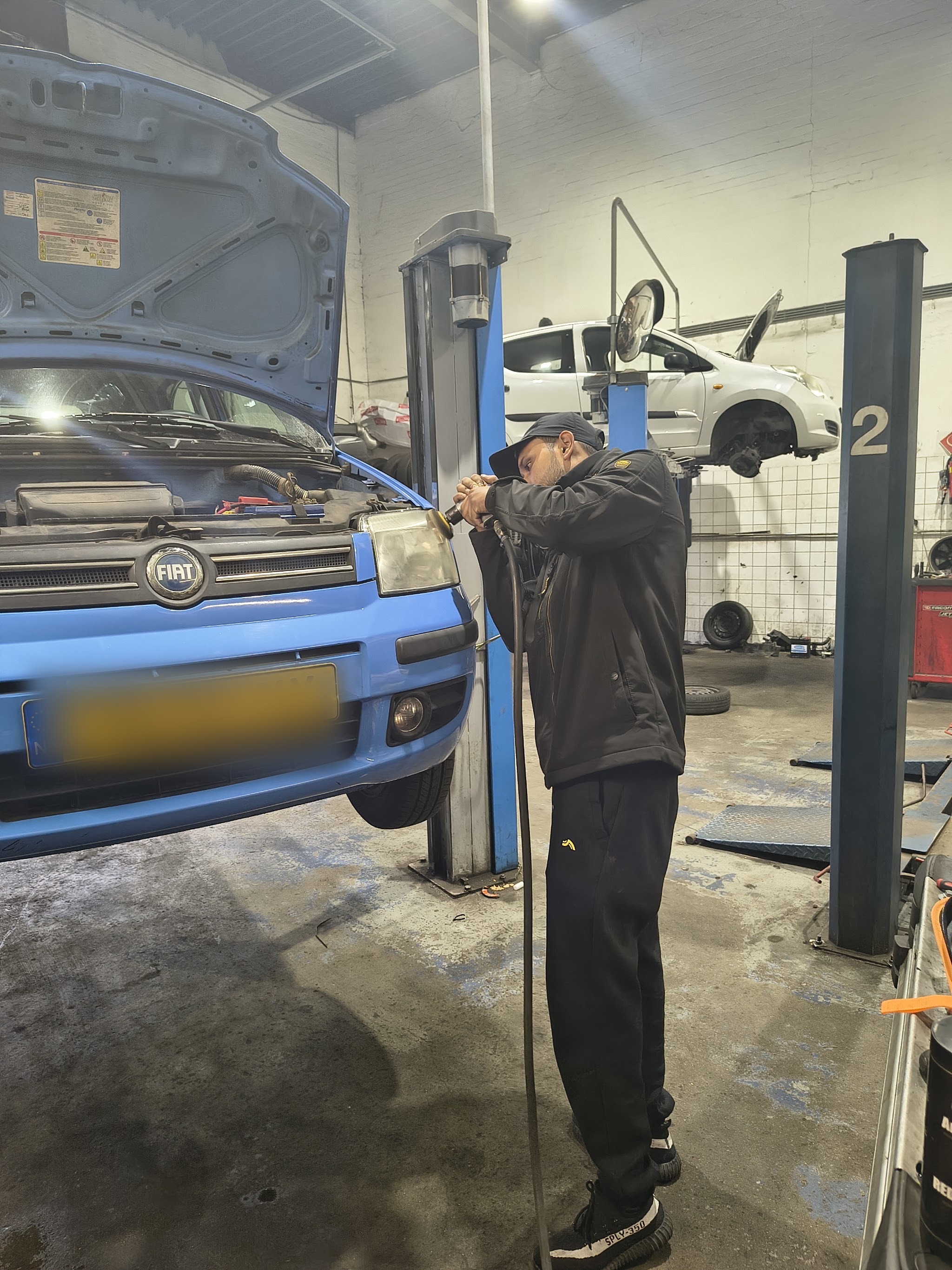 Een monteur werkt aan een auto op de brug in de werkplaats